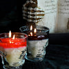 Two lit candles in glass holders with a dark background